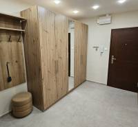 Chodba v 2-pokojovém bytě s nábytkem s dřevěným dekorem a vestavěným zrcadlem.