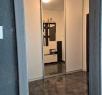 Chodba v 3-pokojovém bytě s dlažbou a vestavěnou skříní.