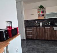 Kuchyně v 3-pokojovém bytě s moderními spotřebiči a dekorativním dřevem.