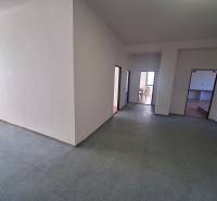 Volný prostor kanceláří s bílými stěnami a linoleovou podlahou.