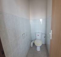 Toaleta v budově s keramickými obklady a dlažbou.