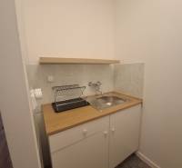 Kuchyňský kout s dřezem a odkapávačem, Budova, světlé obklady, bílá skříňka.