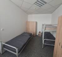 Interiér budovy s postelemi a skříněmi, podlaha s dřevěným dekorem.