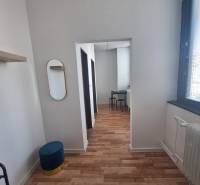 Interiér budovy s podlahou s dřevěným dekorem, židle, zrcadlo, bílý strop.