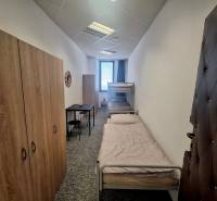 Interiér budovy s dvěma postelemi, skříněmi a malým stolkem na pokoji.