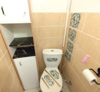 Toaleta v 1-pokojovém bytě s dekorem kamenů na obkladech a WC.