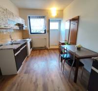 Kuchyně v 1-pokojovém bytě s podlahou s dřevěným dekorem a jídelním stolem.