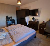 Ložnice v 3pokojovém bytě s pohodlnou postelí, pracovním stolem a podlahou s dřevěným dekorem.