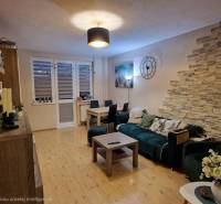 Obývací pokoj v 3pokojovém bytě s podlahou s dřevěným dekorem a dekorativními prvky.