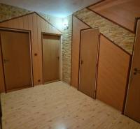 Chodba se třemi dveřmi a podlahou s dřevěným dekorem ve 3-pokojovém bytě.