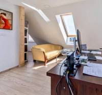 Kanceláře s pohovkou, obrazem na stěně a podlahou s dřevěným dekorem.