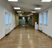 Interiér kanceláří s podlahou s dřevěným dekorem a závěsnými světly.