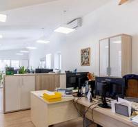 Kanceláře s podlahou s dřevěným dekorem, pracovními stoly a skladovými skříňkami.