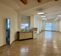 Kanceláře s podlahou s dřevěným dekorem, velkými okny a kuchyňským koutem.