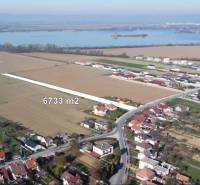 Pozemky k bydlení v Sokolovcích, okolní krajina s vodní plochou v pozadí.