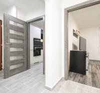 Chodba v 3-pokojovém bytě s podlahou s dřevěným dekorem a vstupem do kuchyně.