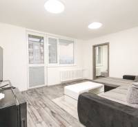 Obývací pokoj s podlahou s dřevěným dekorem, sedačkou a stolkem ve 3pokojovém bytě.