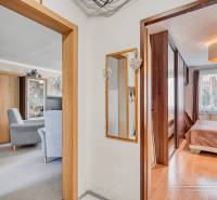 Interiér 4-pokojového bytu s podlahou s dřevěným dekorem, nábytkem a zrcadlem.