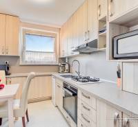 Kuchyně ve 4-pokojovém bytě s ovocem na stole a vestavěnými spotřebiči.