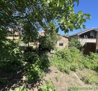 Zahrada u rodinného domu v Tvrdošovcích, obklopená bujnou zelení a stromy.