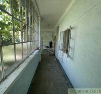 Úzký prosklený prostor v rodinném domě s výhledem na zahradu.