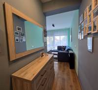 Hala v rekreačním apartmánu s podlahou s dřevěným dekorem a zrcadlem na stěně.