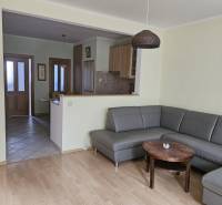 Obývací pokoj s rohovou sedačkou a podlahou s dřevěným dekorem ve 3-pokojovém bytě.