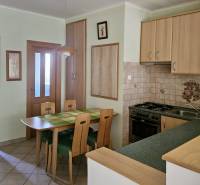 Kuchyně v 3-pokojovém bytě s jídelním stolem a dřevěnými skříňkami.