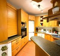 Kuchyně ve 3-pokojovém bytě s rohovou linkou a podlahou s dřevěným dekorem.