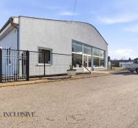 Obchodní prostory v Štúrově s šedou fasádou, parkováním a přístřeškem.