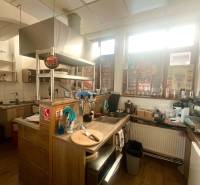 Kuchyně v gastro prostorech s podlahou s dřevěným dekorem, vybavená moderním zařízením.