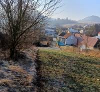 Krajina ve Sklabini s pozemky na bydlení, domy a stromy v pozadí.