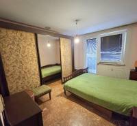 Ložnice ve 3pokojovém bytě s velkou skříní, postelí a zeleným povlečením na posteli.