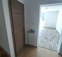 Interiér rodinného domu s dveřmi, radiátorem a podlahou s dřevěným dekorem.