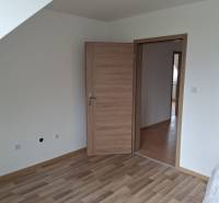 Pokoj v rodinném domě s podlahou s dřevěným dekorem a dřevěnými dveřmi.