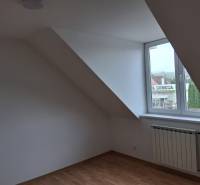 Pokoj pod střechou s oknem a podlahou s dřevěným dekorem v rodinném domě.