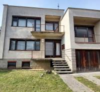 Rodinný dům ve Zlatých Moravcích se schodištěm a balkonem, před ním je zelený trávník.