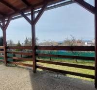 Zahrada a terasa rodinného domu ve Zlatých Moravcích s dřevěnou pergolou.