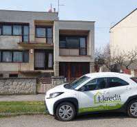 Rodinný dům ve Zlatých Moravcích se zaparkovaným autem realitní kanceláře před domem.