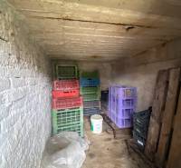 Skladovací prostor v rodinném domě obsahuje plastové bedny a kbelík.