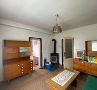 Obývací pokoj v rodinném domě s dřevěným nábytkem a kamny na topení.