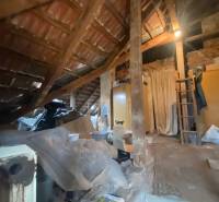 Podkroví rodinného domu se střešní konstrukcí a uskladněnými předměty pod střechou.