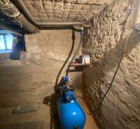 Sklep rodinného domu s čerpadlem a jednoduchými betonovými stěnami.