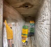 Úzký kamenný sklad v rodinném domě s plastovými přepravkami na zeleninu.