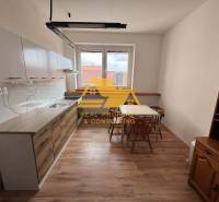 Kuchyně v 1-pokojovém bytě se stolem, židlemi a podlahou s dřevěným dekorem.