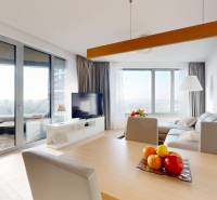 Obývací pokoj v 3-pokojovém bytě s podlahou s dřevěným dekorem a výhledem z balkonu.