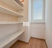 Malý pokoj v rekreačním apartmánu s policemi a oknem, podlaha s dřevěným dekorem.