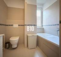 Koupelna v rekreačním apartmánu s vanou, toaletou a moderními obklady.