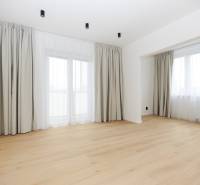 Pokoj v 3-pokojovém bytě s podlahou s dřevěným dekorem a velkými okny.