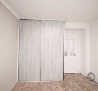 Šatník s posuvnými dveřmi v 2-pokojovém bytě, podlaha s dřevěným dekorem.